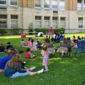 Hawk Creek animal handler talks to program attendees with African serval on a table