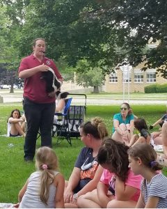 Hawk Creek animal handler holding striped skunk during program