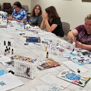 instructor Patience Wnek talks while participants assemble charms