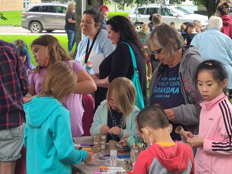 crowd of children and adults with variety of craft supplies on tables