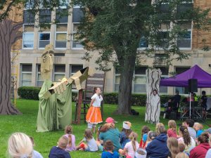 Actor and giant puppet perform for a crowd