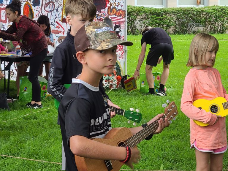 close up of 2 boys and 1 girl with ukuleles