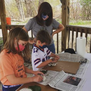 boy and girl work on self portraits with adult woman in background