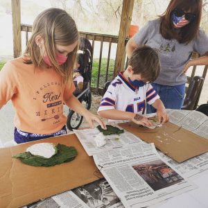 boy and girl work on self portraits with adult woman