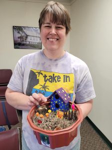 adult in grey tshirt shows fairy garden in octagonal container in