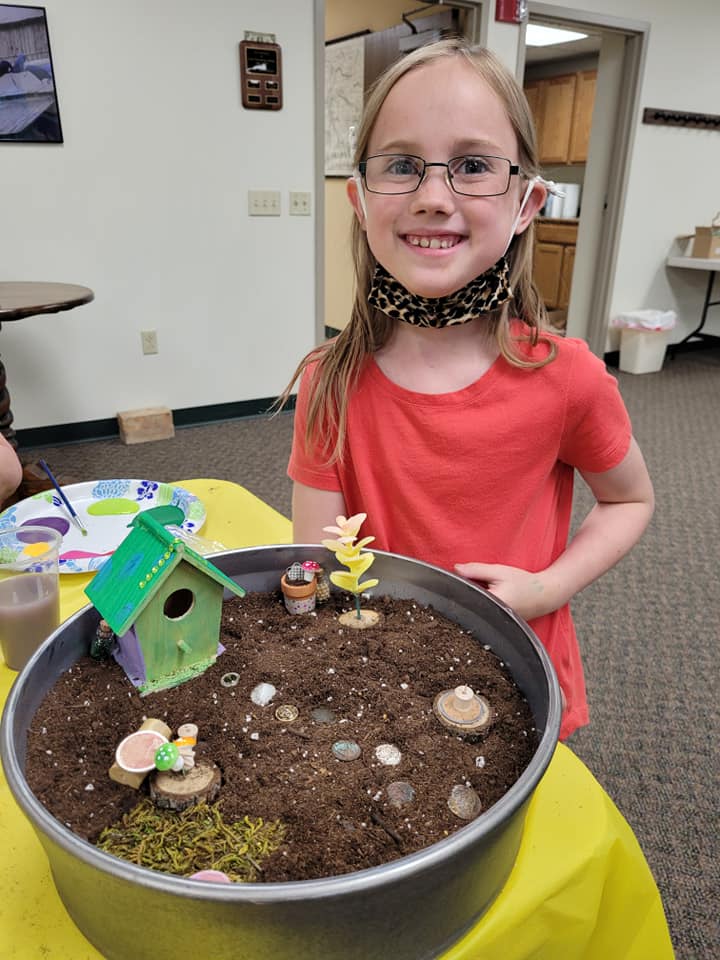 girl in red shirt with fairy garden in round container