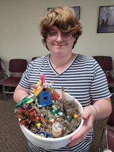 adult in striped shirt with fairy garden in round container