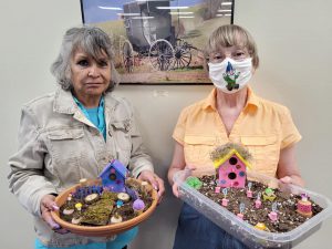 two women with fairy gardens, one in a round container, one in a rectangular one