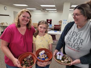 two women and a girl in a yellow shirt with fairy gardens in round containers