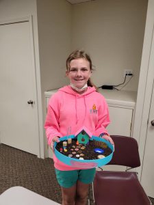 girl in pink sweatshirt with fairy garden in round container