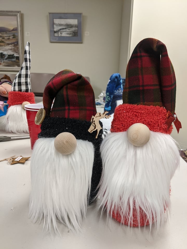 two gnomes with red and black plaid hats, one with black accents, one with red accents.