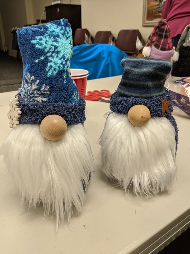 one gnome with blue hat with snowflake pattern, one gnome with blue striped hat