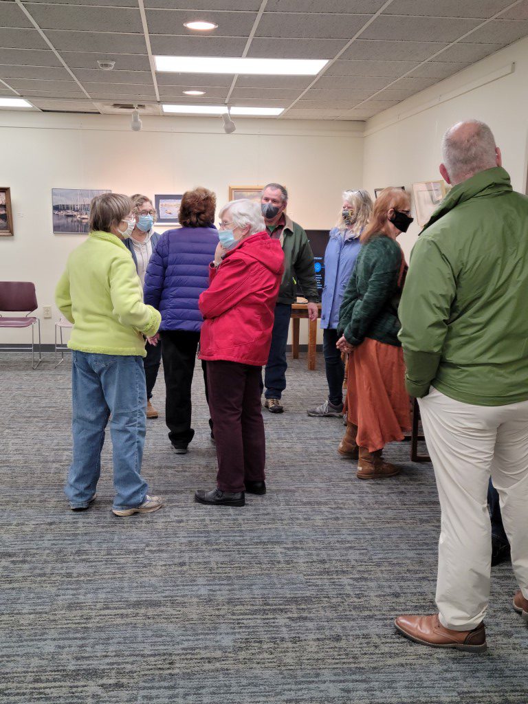 Patrons and board members talk in small groups during the library open house.