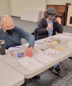 man and boy work on watercolor paintings