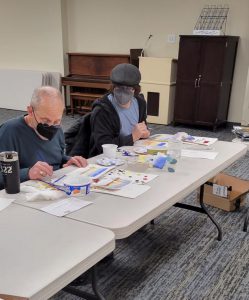 man and boy work on watercolor paintings