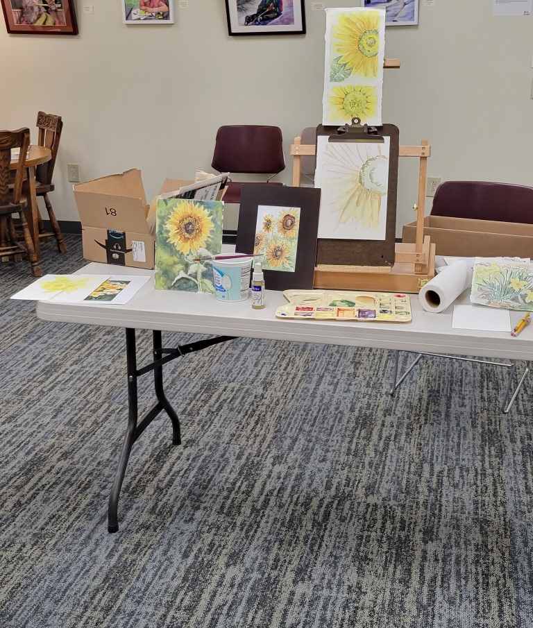 display of multiple watercolor paintings of sunflowers done by the class instructor