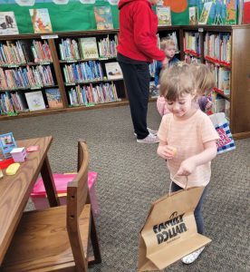 young girl with paper bag looks for Easter eggs