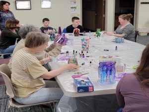 several patrons sit at tables with finished projects waiting for the alcohol inks to dry