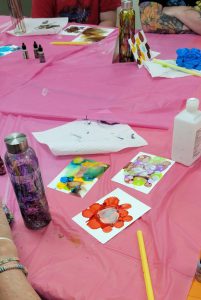 water bottle with several colors sits next to papers with red, blue, green and yellow, and purple green and pink spots