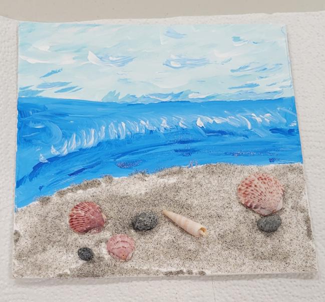an ocean scene with a sand beach and shell and pebble embellishments