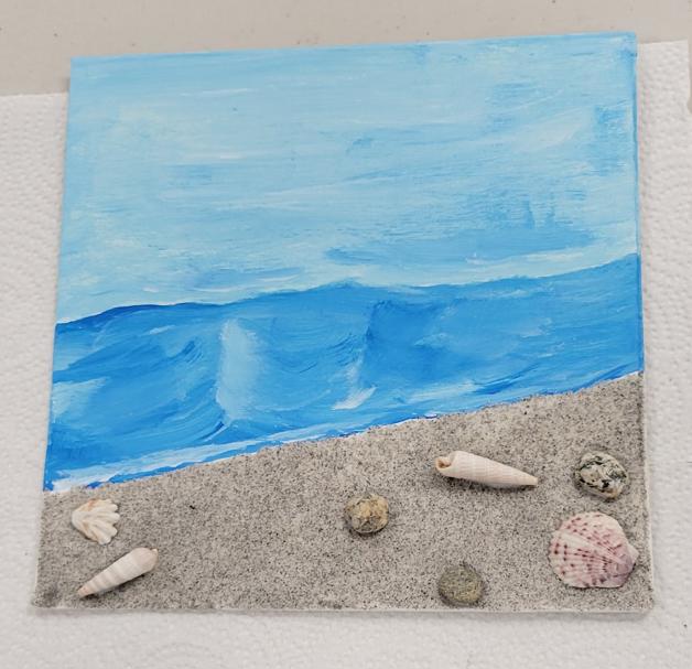 a beach scene with sand, pebble, and shell embellishments