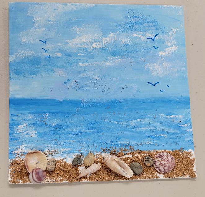 canvas painted with a beach scene with crushed walnut shell sand, seashell embellishments, and blue 'seagull' outlines in the sky