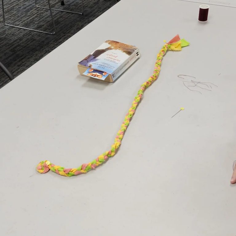 a braided fabric rope of yellow pink and green sits on a table