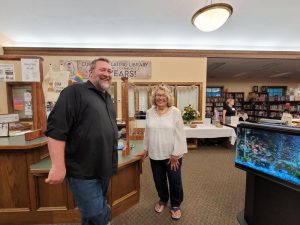 man with beard in black button down laughs with woman with curly greying blond hair in white blouse