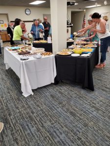 several people visit a trio of tables laden with hors d'oeuvres