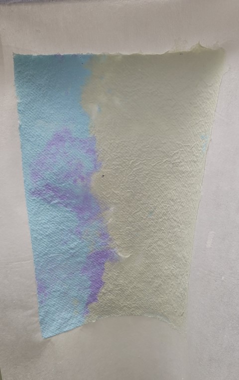 handmade paper that is half pale green and half blue with purple swirls