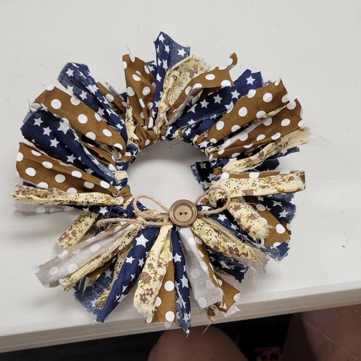 wreath made with strips of fabric in navy with white stars, brown with white polka dots, and cream with mauve flowers