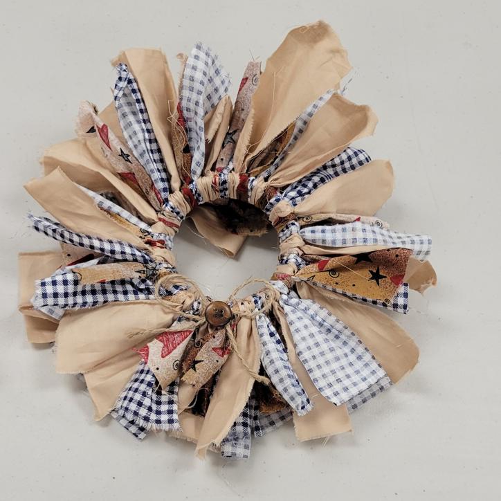 wreath made with strips of fabric in tan, blue gingham, and tan with blue stars and red hearts