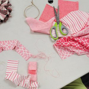 fabric in shades of magenta pink and white in different patterns sits on a table with lime and grey handled scissors