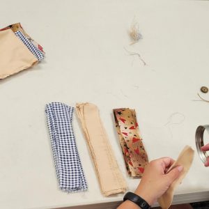 fabric strips of blue gingham, tan, and tan with hearts and stars sit on a table