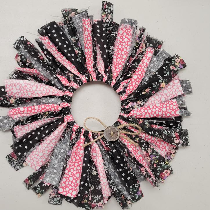 wreath made with strips of fabric in black floral, black with white stars, and magenta with white dots