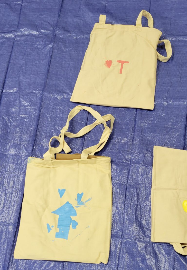tan tote bags one with pink T and heart, one with blue arrow and hearts