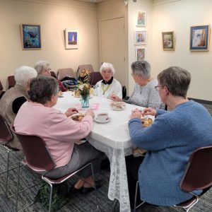 a table of ladies converse while having tea and hors d'oeuvres