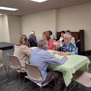 two tables of people converse while having tea and hors d'oeuvres