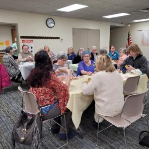 three tables of people enjoy tea and hors d'oeuvres