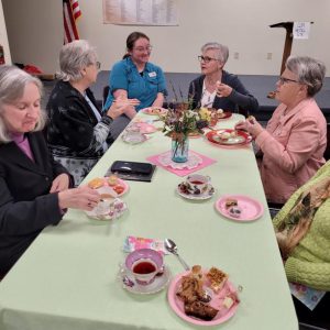 Table of ladies chats while enjoying tea and cookies