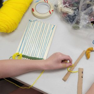 weaving project with green yarn on a small weaving loom