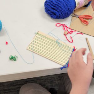 weaving project with red and royal blue yarn on a small weaving board