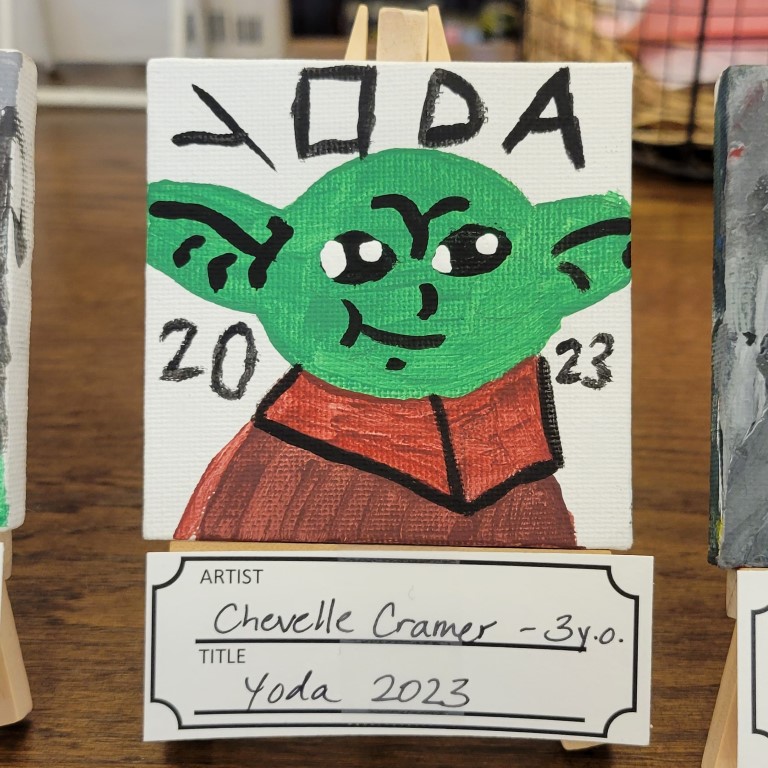 painting of green alien with pointed ears and brown cloak with lettering yoda 2023 around it