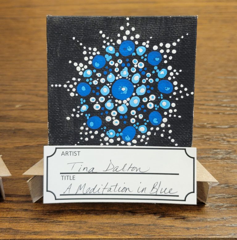 black painting with mandala pattern of white, light blue, and dark blue dots
