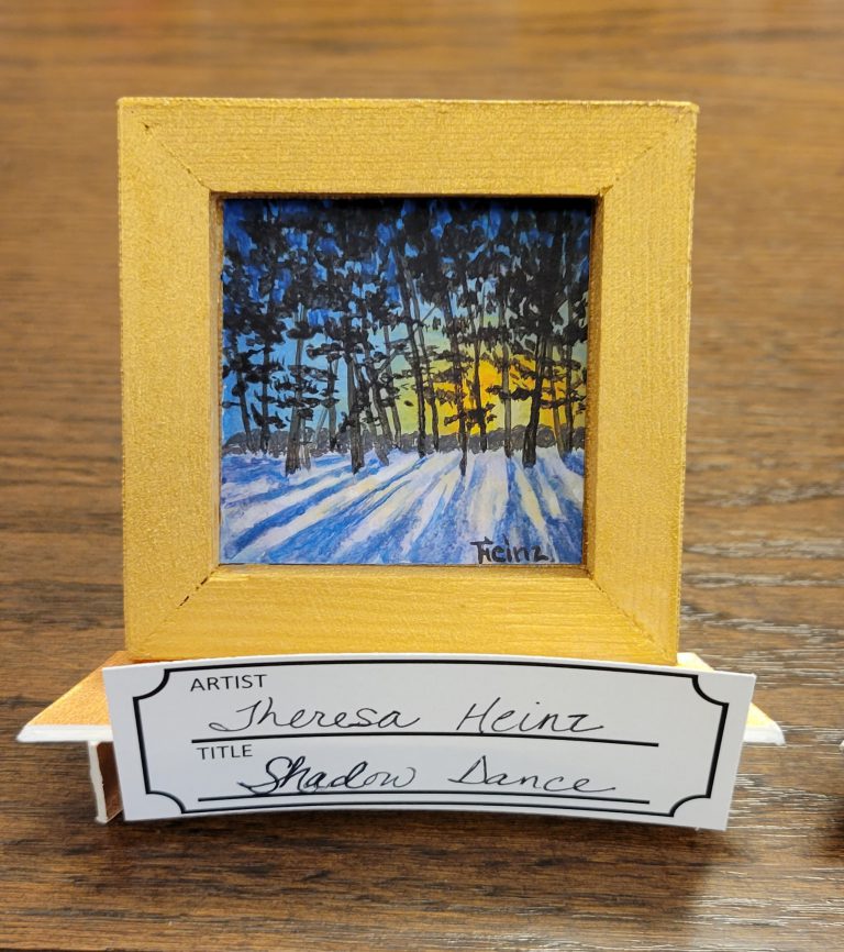 Painting on reverse side of canvas with wood frame painted gold with blue and yellow sunset/sunrise through black trees and snowy ground with blue shadows