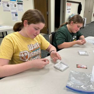 two young girls stringing beads