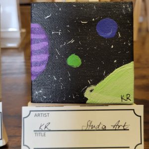 black painting with yellow splatters, a small green and a small purple circle, a partial round light and darker purple striped object on the left, and a green curved wedge with a yellow line in the lower right corner