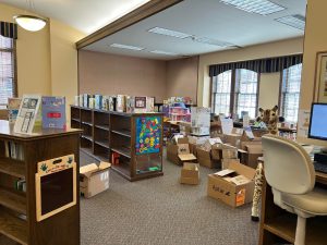 partially emptied shelves of picture books with large pile of boxes