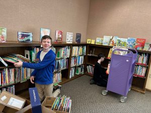 teen boys pack boxes and a book cart