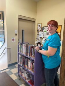 woman with full book cart smiles at camera